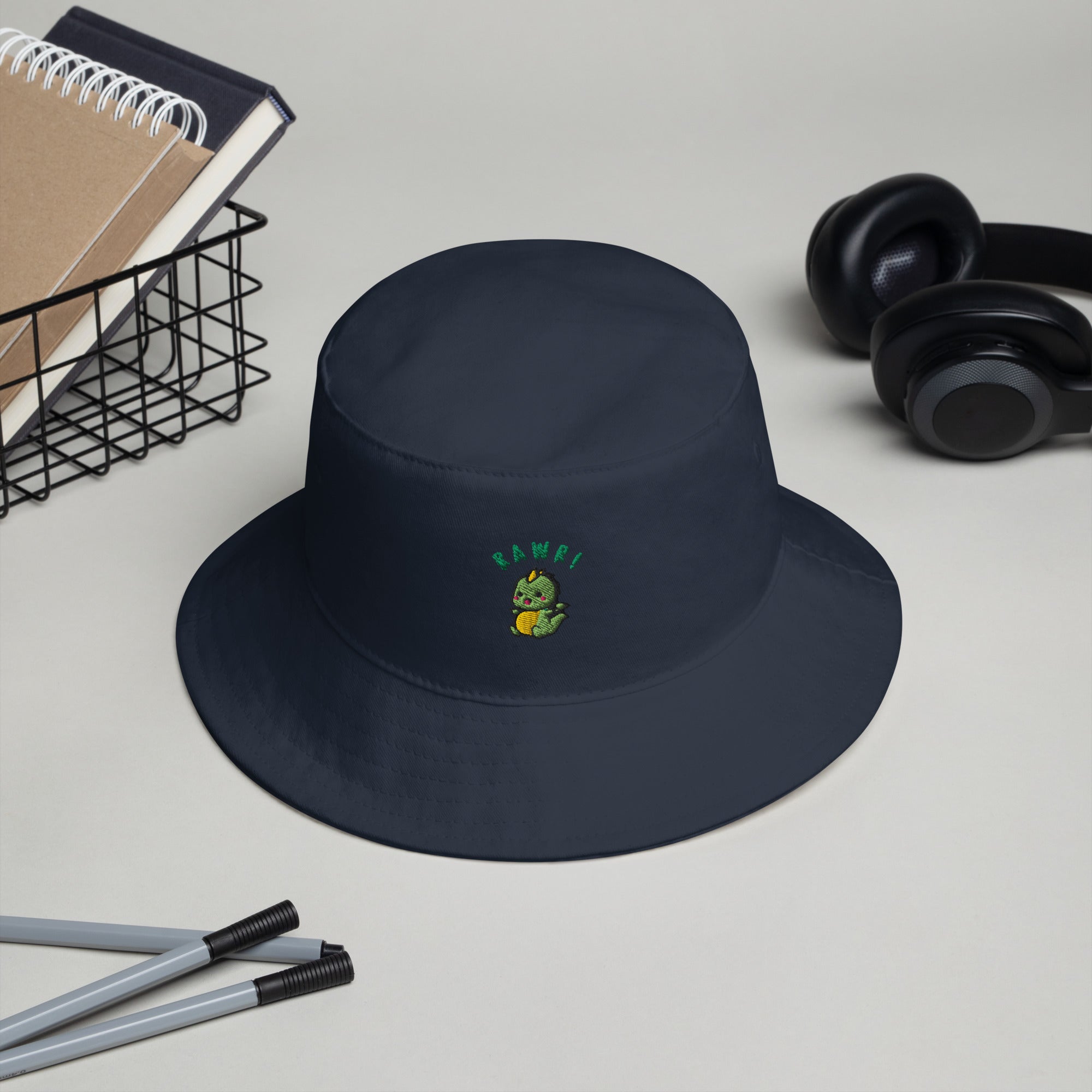 Blue Marine Baby Dino Bucket Hat displayed on a desk, showcasing its playful design and perfect size.