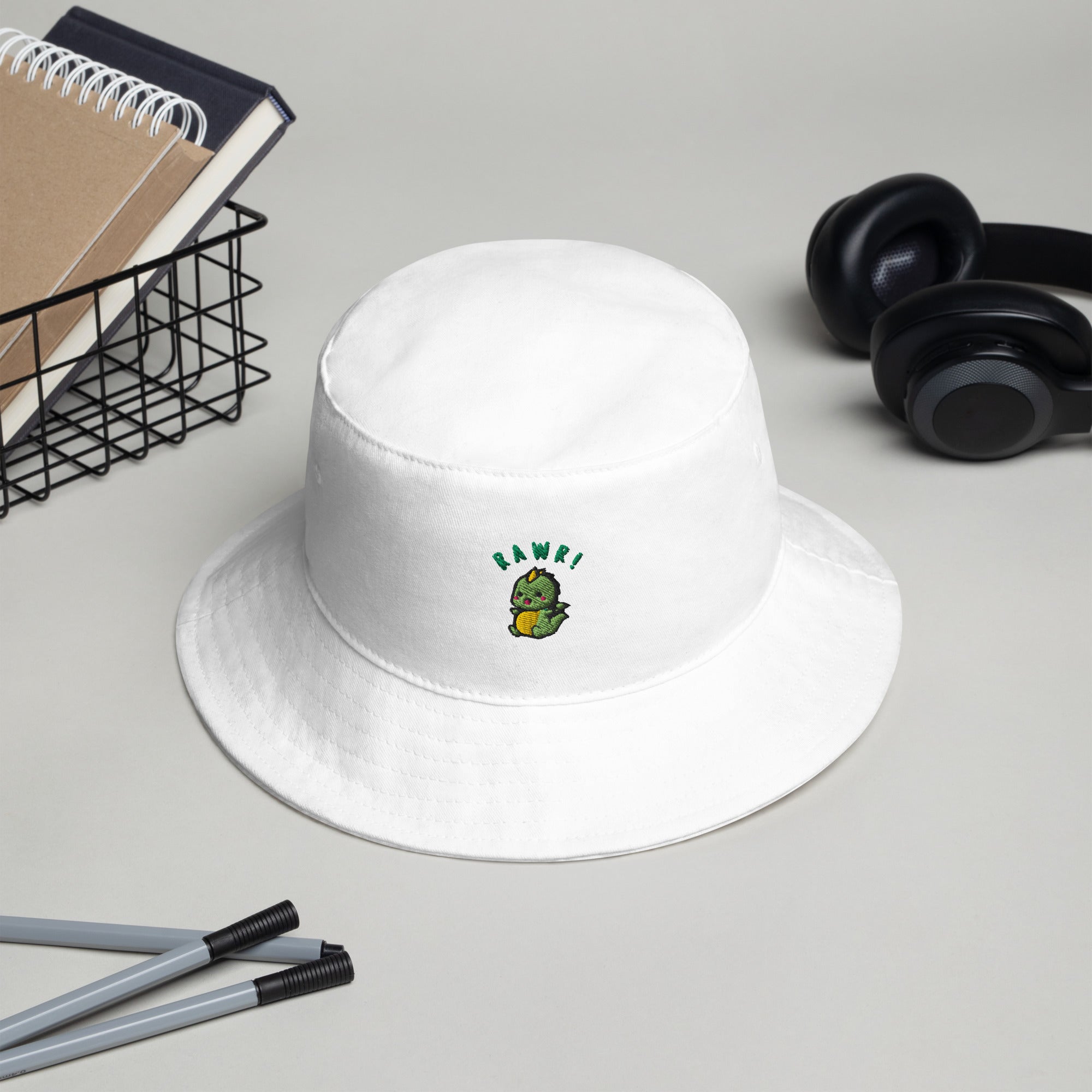 White Baby Dino Bucket Hat placed on a desk, showcasing its clean design and potential for personalization.