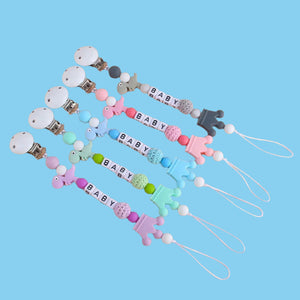 Little Dino Silicone Pacifier Chain in pink, purple, green, and blue, showcasing the variety of color options available.